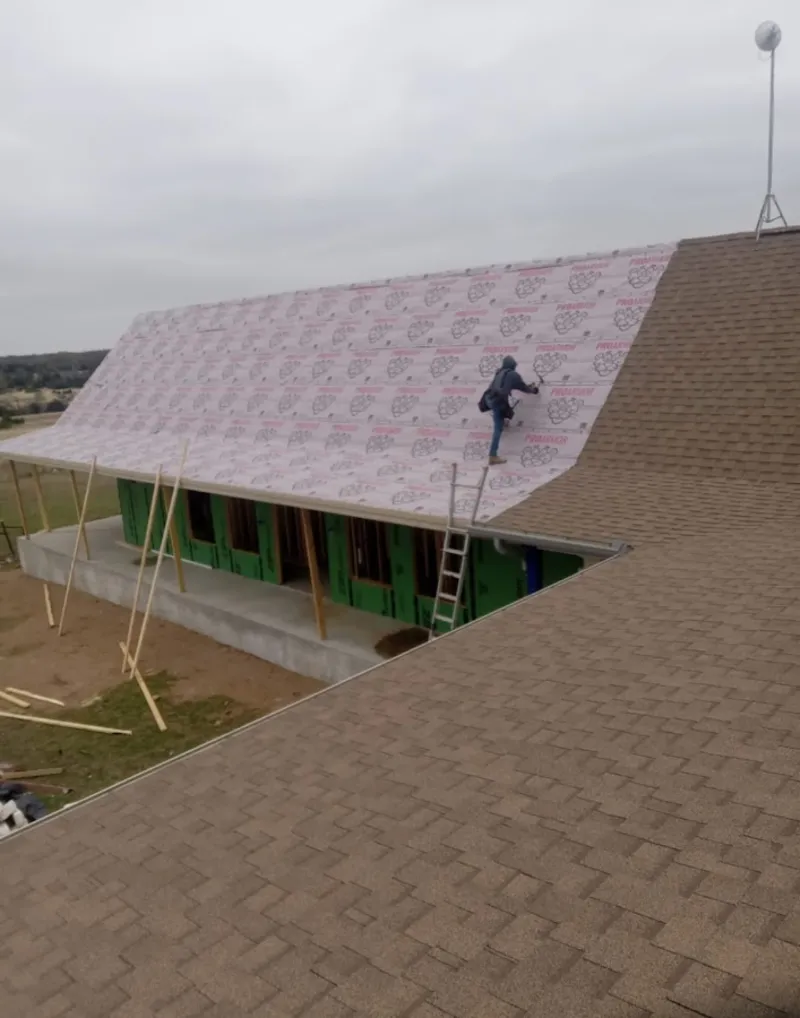 Worker preparing underlayment for a metal roof installation in Ken Caryl